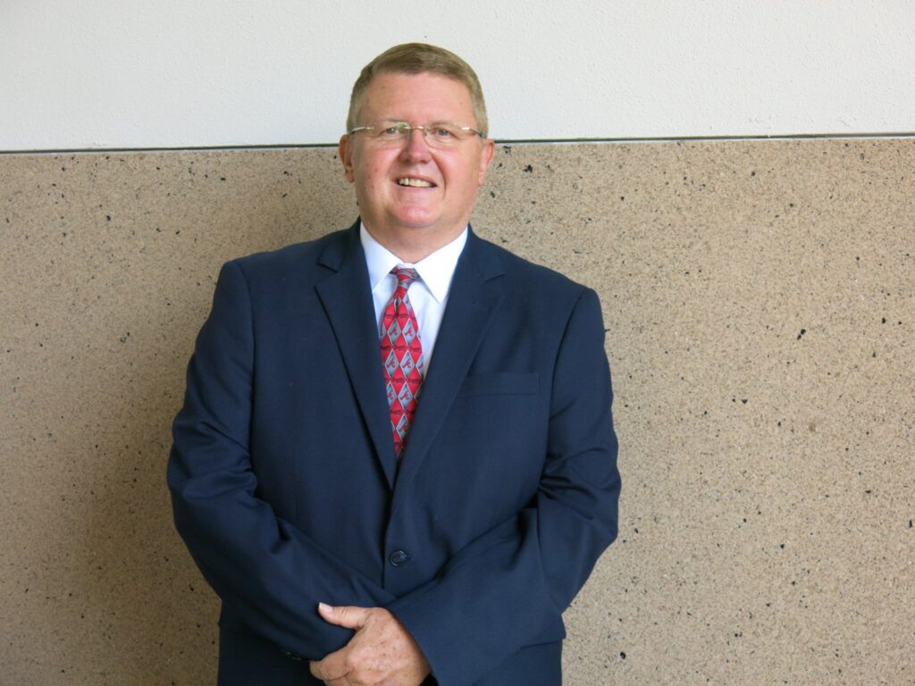 Smiling man in navy suit and patterned red tie