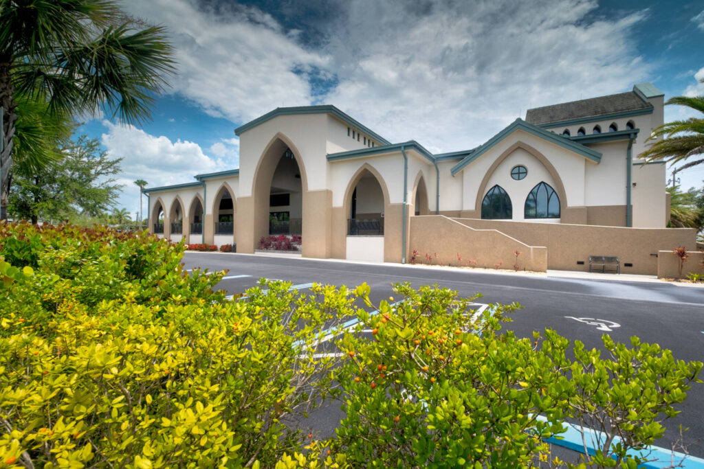 Church exterior with Gothic arches beside accessible parking