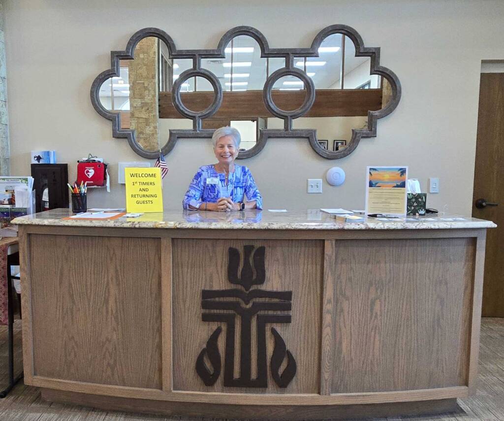 Smiling receptionist behind wooden welcome desk