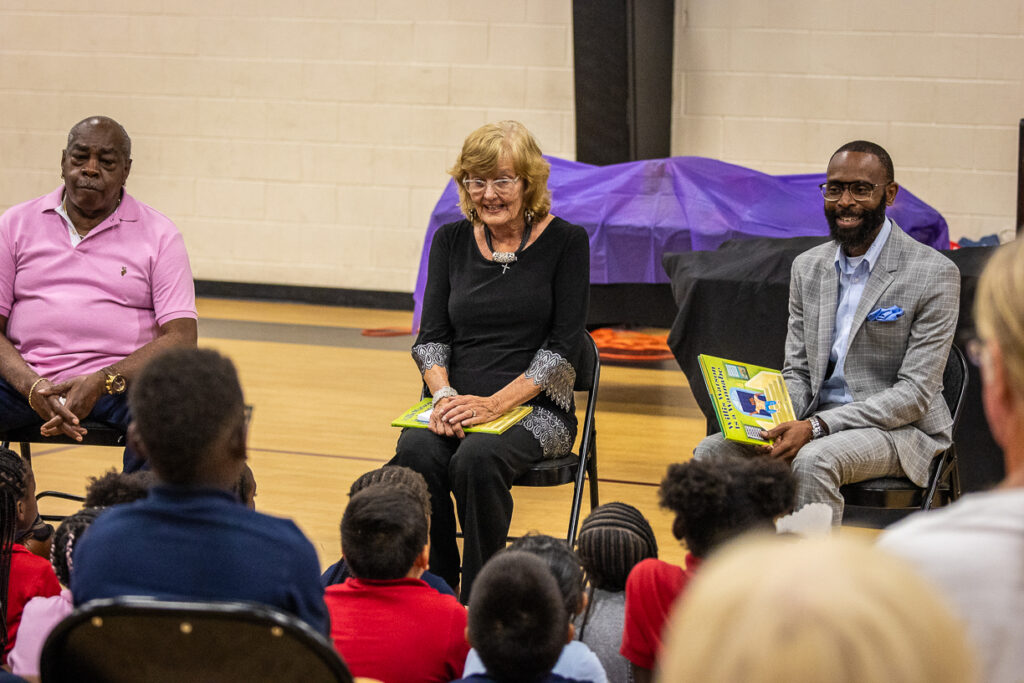 Adults read with children during a school gathering