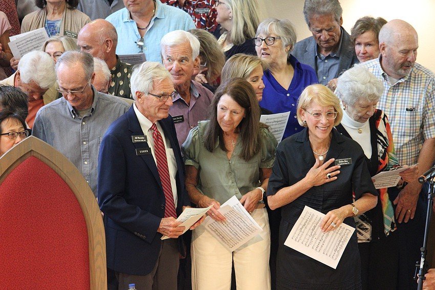 Older adults gather holding sheet music at a church.